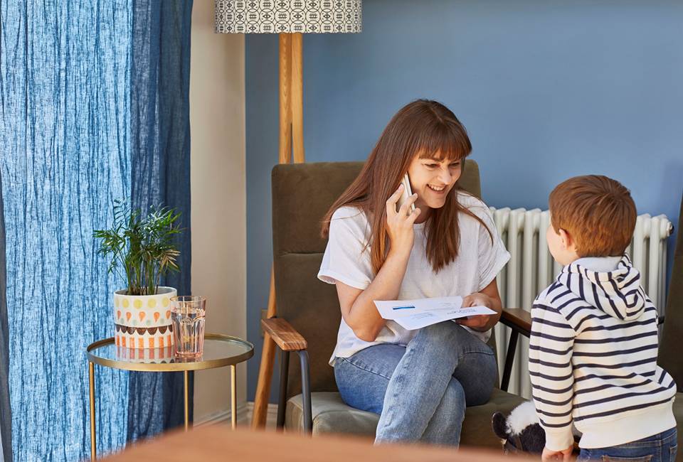 A Yorkshire Water customer smiles at a child, while on the phone and holding a letter from Yorkshire Water