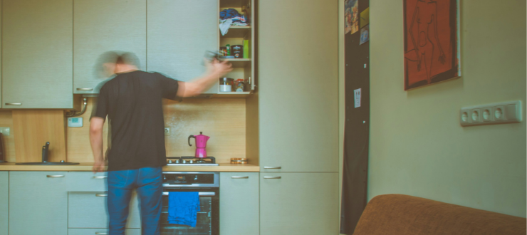 An energy customer stands in their kitchen facing their oven.
